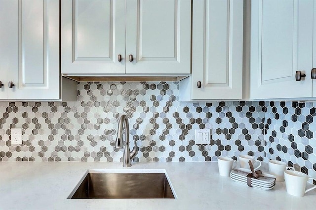 kitchen featuring white cabinetry, sink, and tasteful backsplash