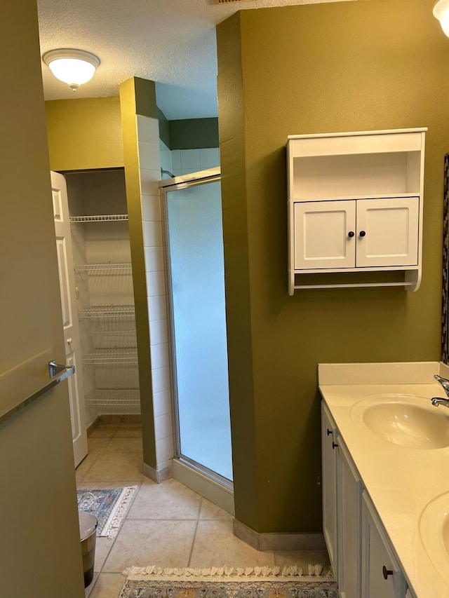 bathroom with tile patterned flooring, vanity, a shower with door, and a textured ceiling