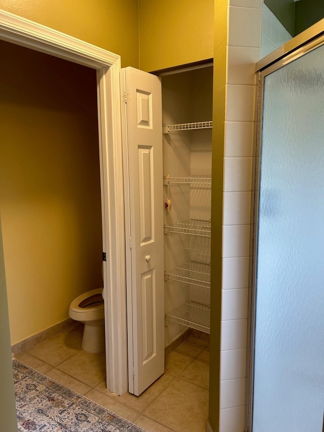 bathroom featuring tile patterned floors, toilet, and an enclosed shower