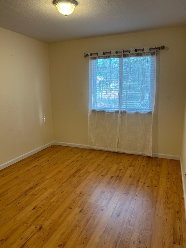 unfurnished room featuring a textured ceiling and light hardwood / wood-style flooring