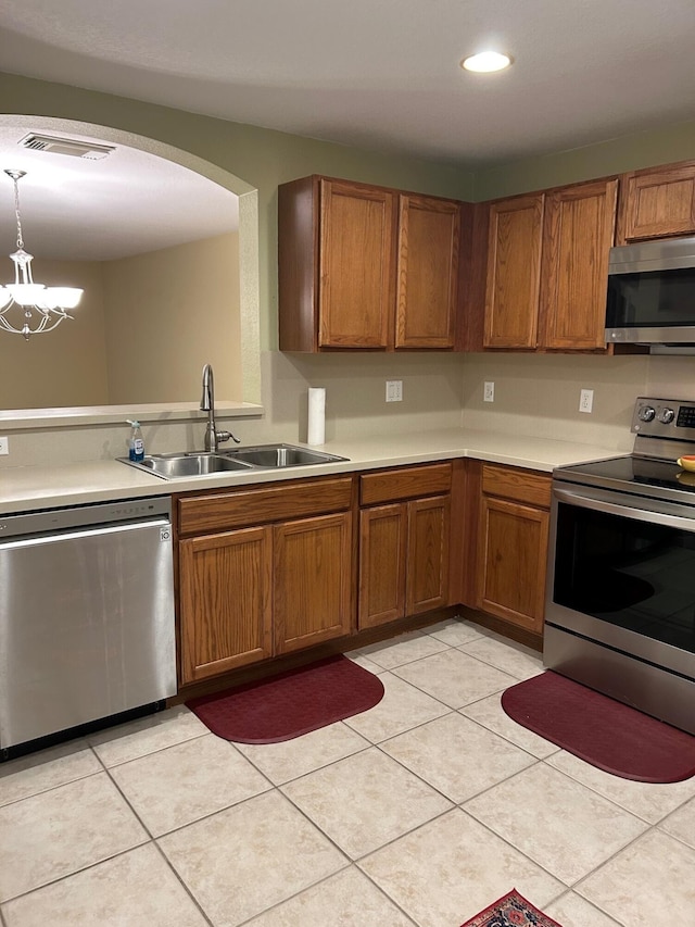 kitchen with an inviting chandelier, sink, light tile patterned floors, decorative light fixtures, and stainless steel appliances