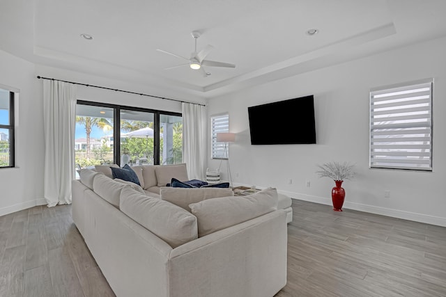 living room featuring a tray ceiling and light hardwood / wood-style flooring