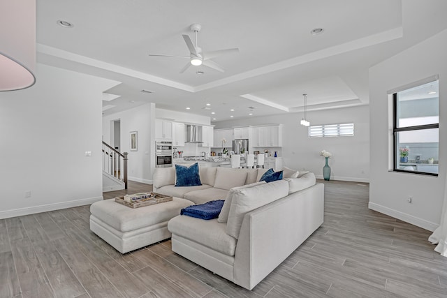 living room with ceiling fan and a raised ceiling