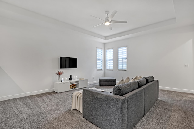 carpeted living room with ceiling fan and a tray ceiling