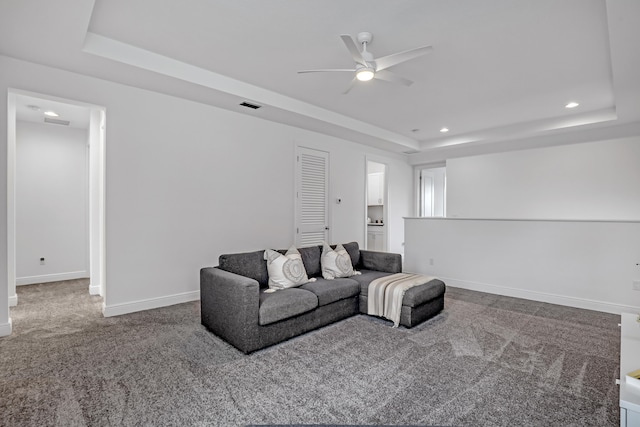 carpeted living room featuring ceiling fan and a tray ceiling