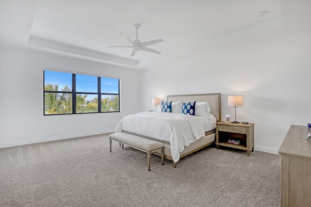 carpeted bedroom featuring ceiling fan and a raised ceiling