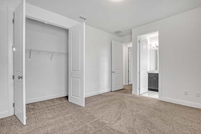 unfurnished bedroom featuring light carpet, a closet, and connected bathroom