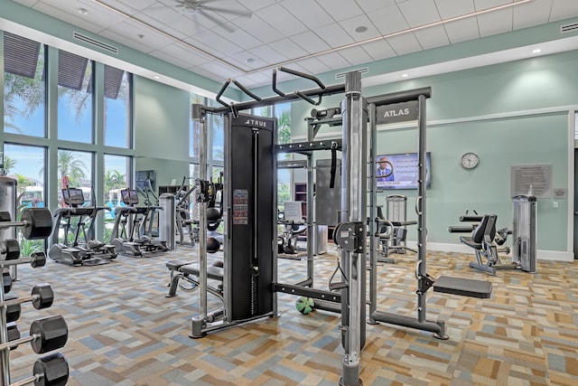 exercise room with a high ceiling, ceiling fan, and carpet floors