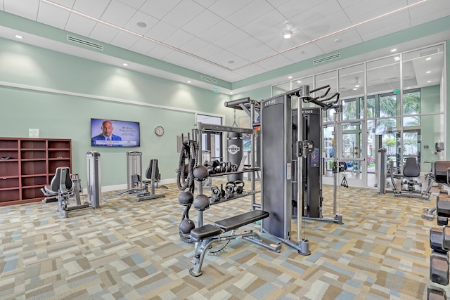 gym with light carpet and a towering ceiling