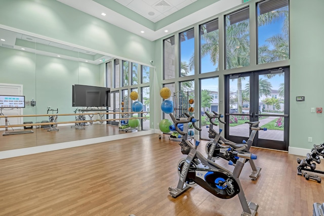 gym with a high ceiling, wood-type flooring, and french doors