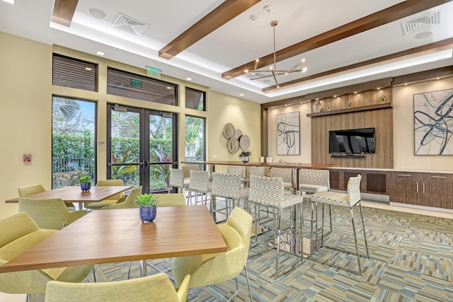 dining space with a raised ceiling, french doors, and a chandelier