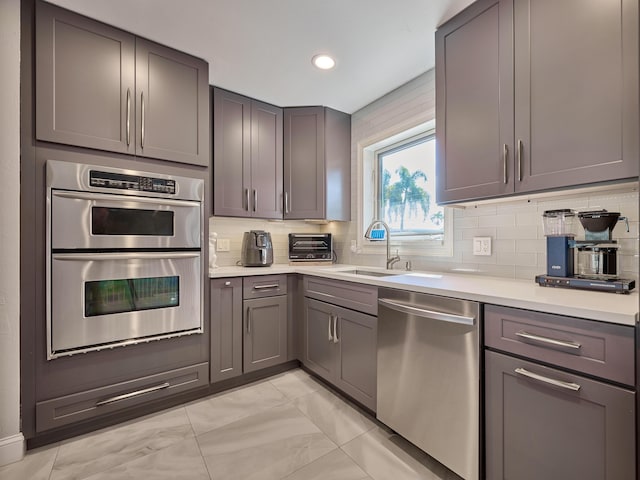 kitchen featuring stainless steel appliances, light countertops, gray cabinetry, and recessed lighting