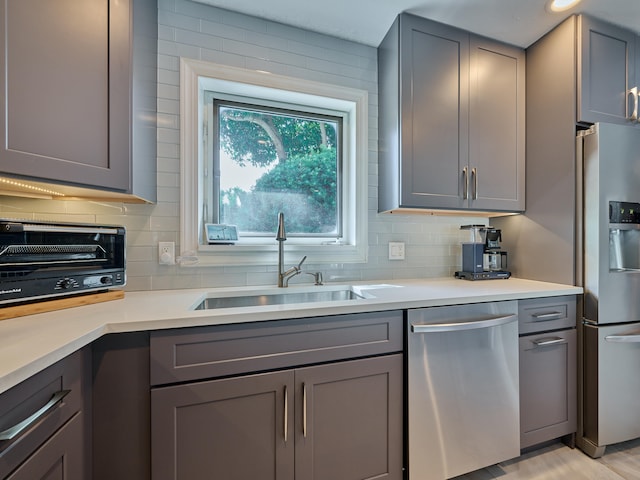 kitchen with decorative backsplash, stainless steel appliances, sink, and gray cabinetry