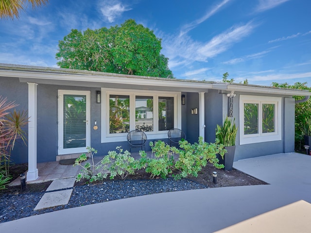 doorway to property featuring stucco siding and a porch