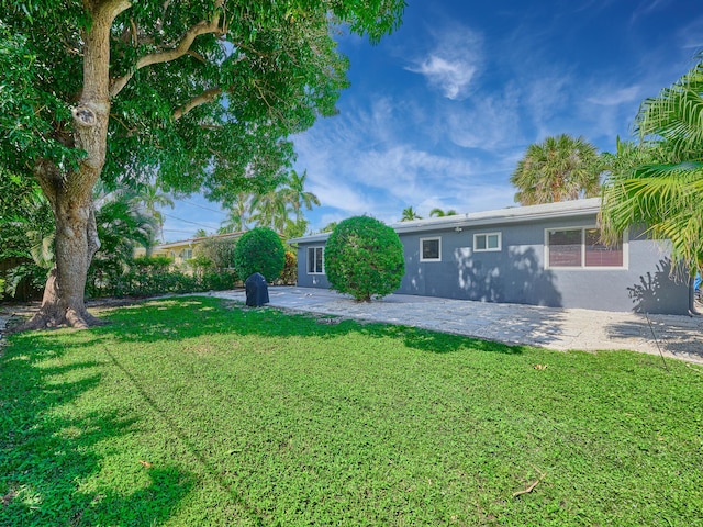 rear view of property with a yard, stucco siding, and a patio area