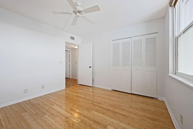 unfurnished bedroom featuring multiple windows, a closet, light wood-type flooring, and ceiling fan