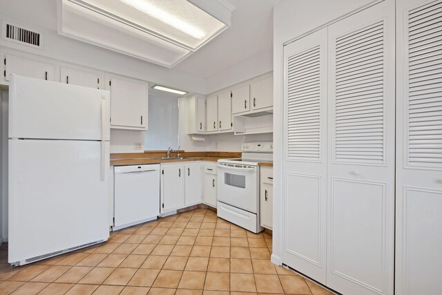 kitchen featuring white appliances, light tile patterned floors, white cabinetry, and sink