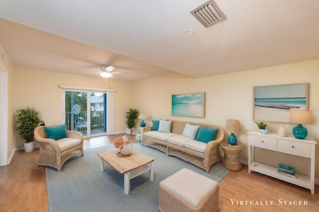 living room with ceiling fan, a textured ceiling, and light hardwood / wood-style flooring