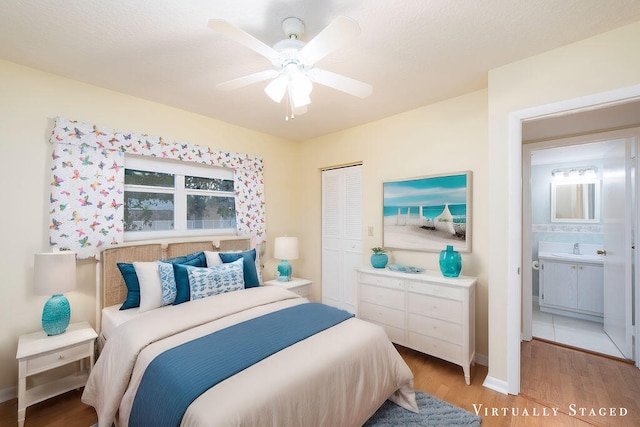 bedroom with ceiling fan, sink, light hardwood / wood-style flooring, a closet, and ensuite bath