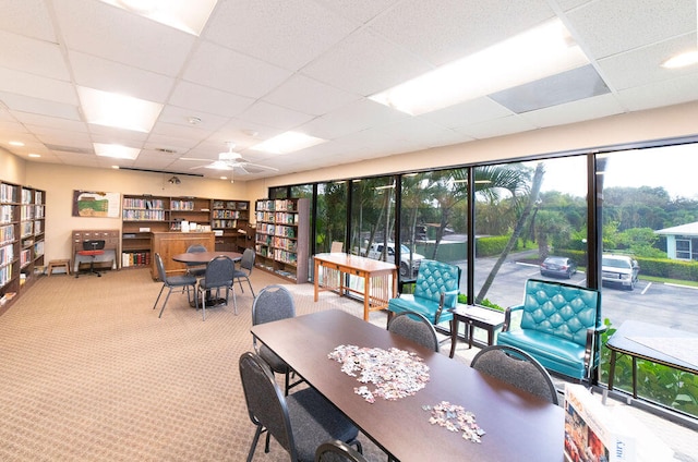 carpeted dining room with a paneled ceiling and ceiling fan