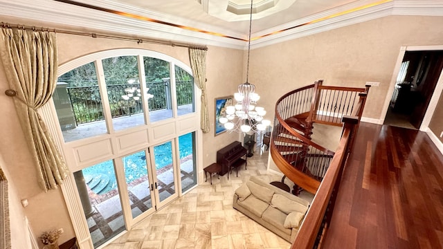 interior space featuring french doors, ornamental molding, a raised ceiling, an inviting chandelier, and hardwood / wood-style floors