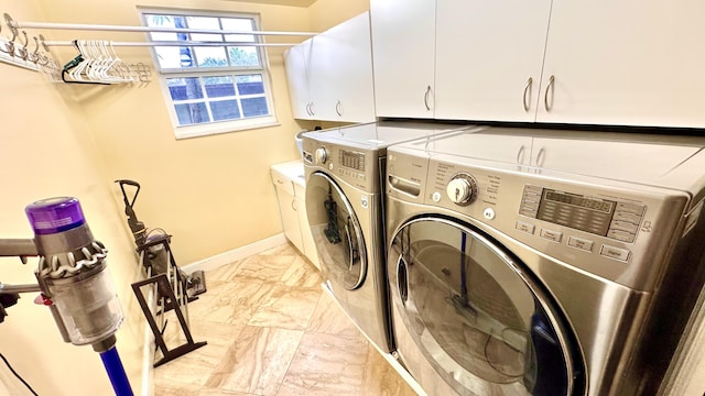 washroom with washer and dryer and cabinets