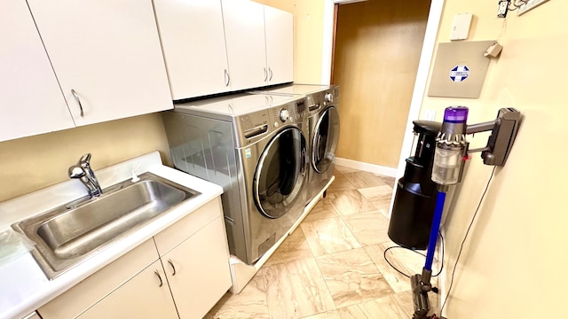 washroom with cabinets, washer and dryer, and sink