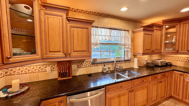 kitchen with dishwasher, dark stone countertops, decorative backsplash, and sink