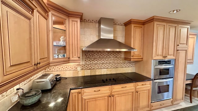 kitchen featuring black cooktop, tasteful backsplash, double oven, and wall chimney exhaust hood