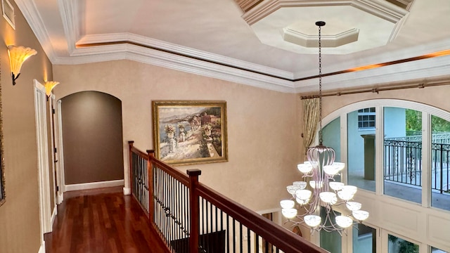 hall featuring dark hardwood / wood-style floors, crown molding, a tray ceiling, and a chandelier