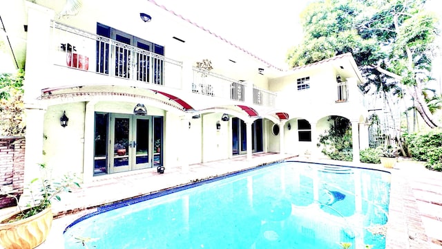 rear view of house featuring a balcony and french doors