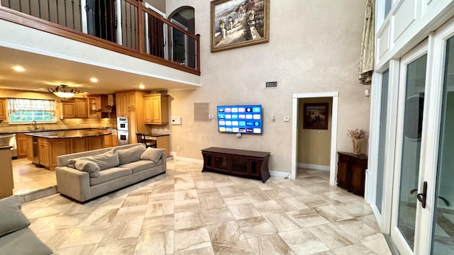 living room featuring a towering ceiling, sink, and french doors