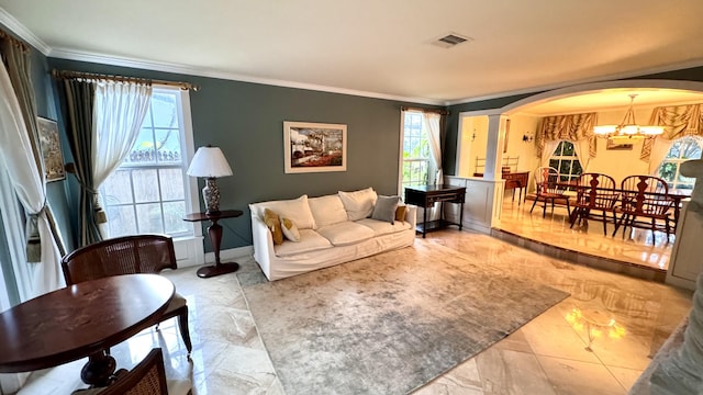 living room featuring decorative columns, a chandelier, a healthy amount of sunlight, and ornamental molding