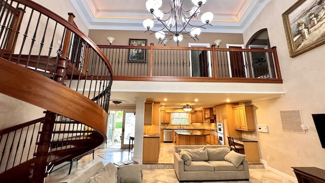 living room featuring a raised ceiling, crown molding, and a chandelier