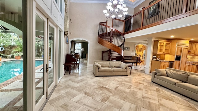 living room featuring ornamental molding, french doors, a high ceiling, and a chandelier