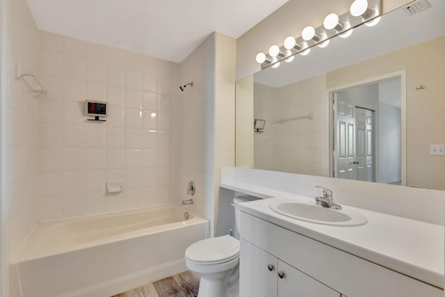 full bathroom with vanity, tiled shower / bath, hardwood / wood-style floors, and toilet