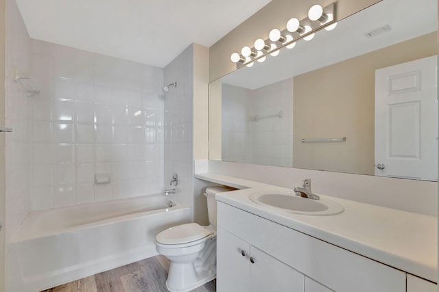 full bathroom featuring vanity, hardwood / wood-style flooring, tiled shower / bath combo, and toilet