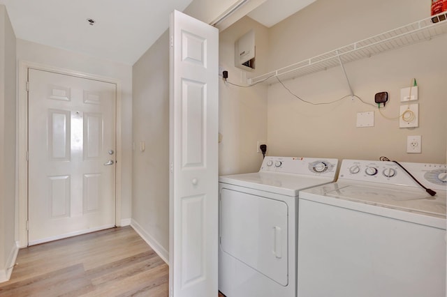 clothes washing area featuring light hardwood / wood-style floors and washer and clothes dryer