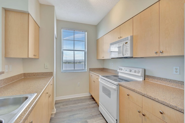 kitchen with light hardwood / wood-style flooring, white appliances, a textured ceiling, and light brown cabinetry