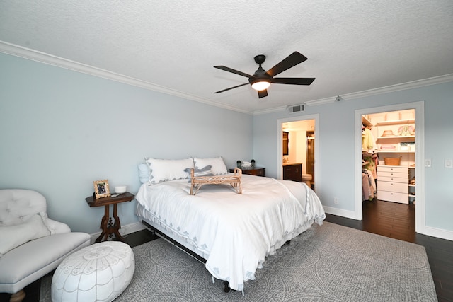 bedroom featuring a spacious closet, a textured ceiling, ceiling fan, dark wood-type flooring, and crown molding