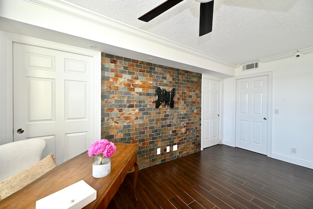 interior space with brick wall, a textured ceiling, dark hardwood / wood-style floors, and ceiling fan