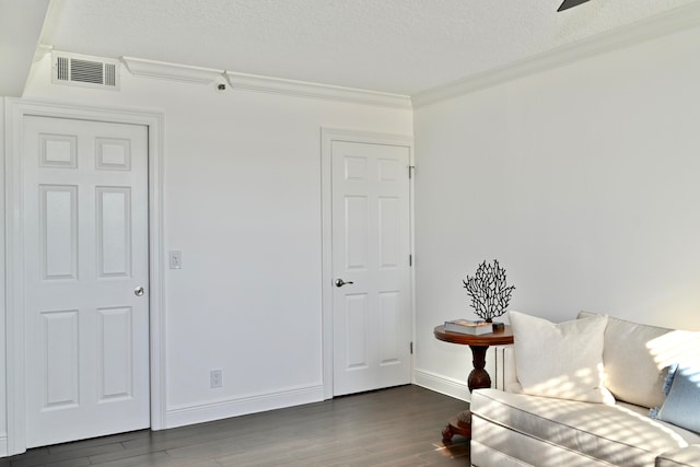 living area with ornamental molding, a textured ceiling, and dark wood-type flooring