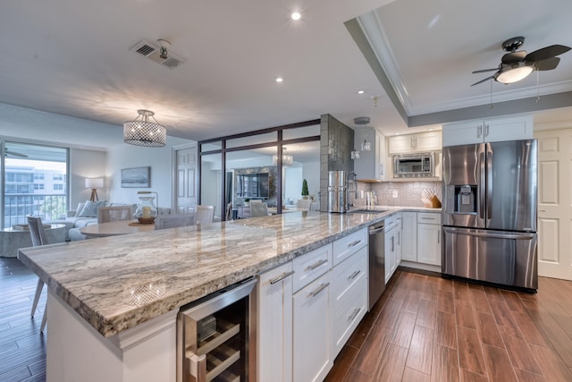 kitchen featuring beverage cooler, appliances with stainless steel finishes, white cabinetry, dark hardwood / wood-style floors, and crown molding