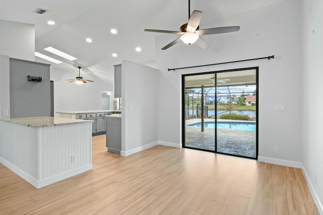 kitchen featuring kitchen peninsula, gray cabinetry, ceiling fan, light hardwood / wood-style flooring, and lofted ceiling