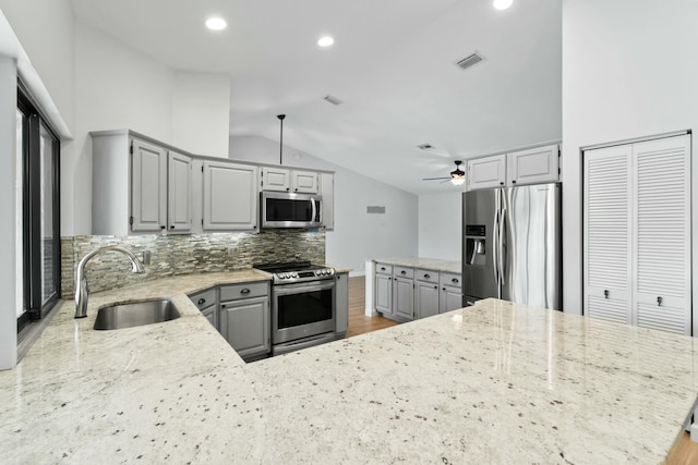 kitchen featuring ceiling fan, sink, stainless steel appliances, backsplash, and lofted ceiling