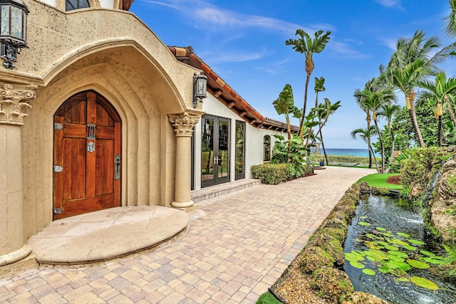 view of exterior entry with a water view and french doors