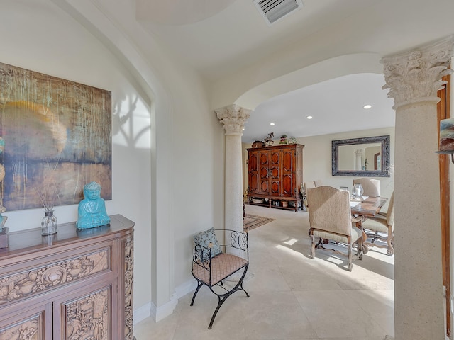 hall featuring decorative columns and light tile patterned floors