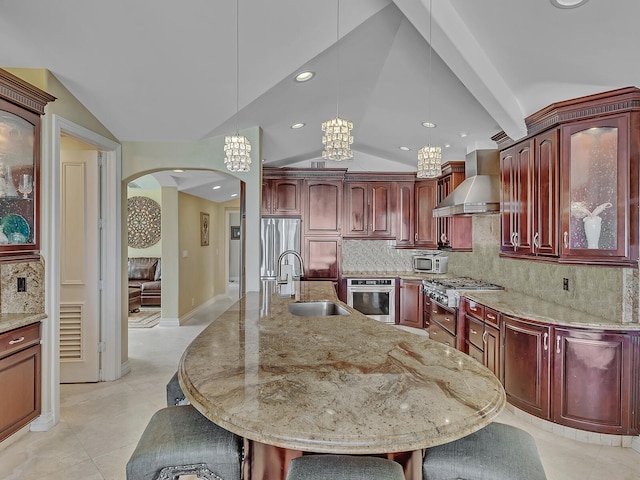 kitchen featuring stainless steel appliances, backsplash, sink, and wall chimney range hood