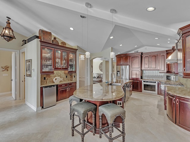 kitchen featuring backsplash, light stone counters, stainless steel appliances, hanging light fixtures, and lofted ceiling