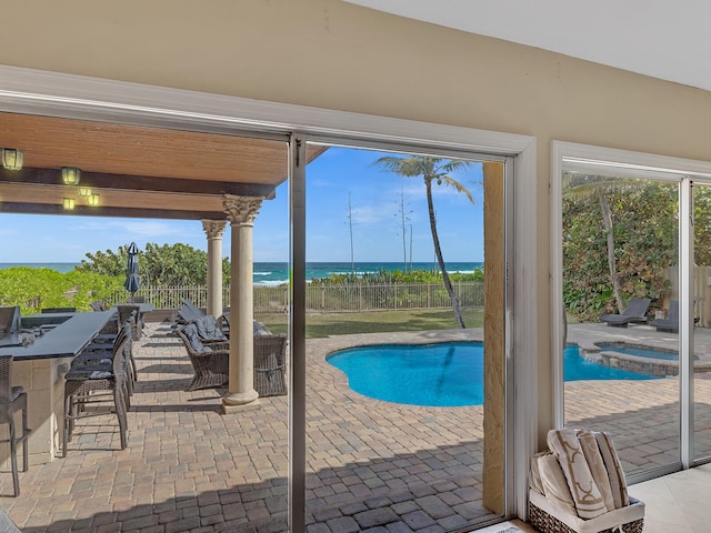 view of swimming pool featuring a water view, a patio area, and an outdoor bar